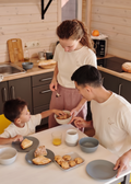 A family of three shares a meal, wearing matching cream-colored t-shirts